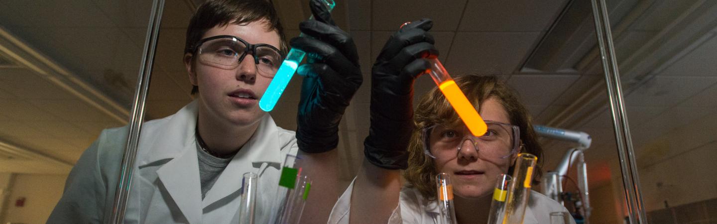 Two students holding glow-in-the-dark tubes 