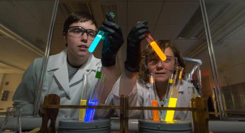 Two students holding glow-in-the-dark tubes 