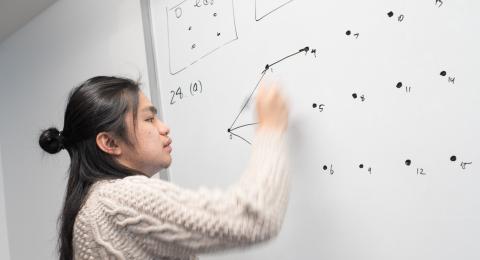 Math statistics major student practicing mathematical equations on a white board.