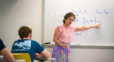 Professor in front of a white board with math equations