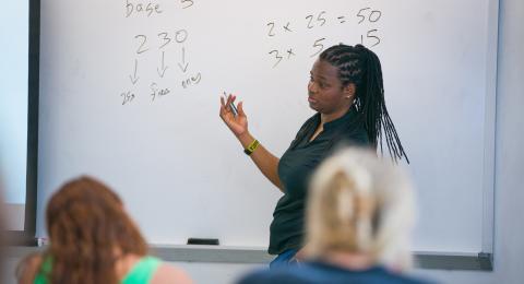 professor writing math equations on a whiteboard 
