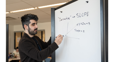 Student writing mathematic equations on a whiteboard