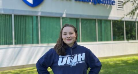 Sarah Souliere stands below the Olson Center UNH sign