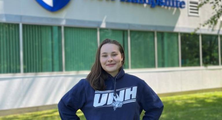 Sarah Souliere stands below the Olson Center UNH sign
