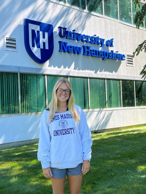 Communications Intern Jesse Davis stands underneath the UNH Sign outside of the Olson Center